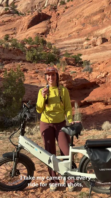 Cover frame of Lectric's pannier bag video: a rider stands by a white Lectric e-bike with a black bag on red desert rocks