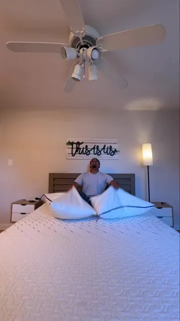 A man sitting on a bed holding open a pillow, from Nectar's Tri-comfort pillow post, its most-viewed ad-flagged post