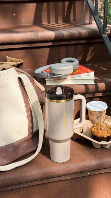 A cream Stanley tumbler with coffee and a pastry on outdoor steps, Stanley's fall collection teaser and its most-viewed recent post.